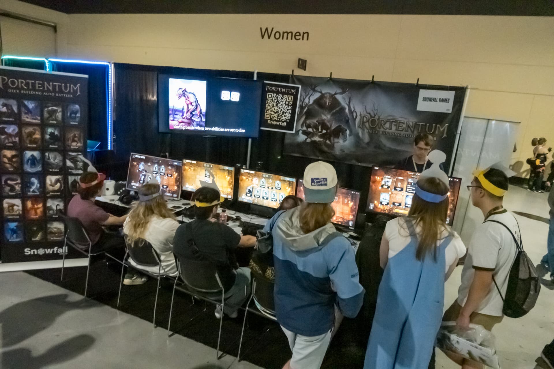 Every seat at the Portentum booth taken, players in paper cryptid headbands mid-run, with more people standing behind them waiting for a turn