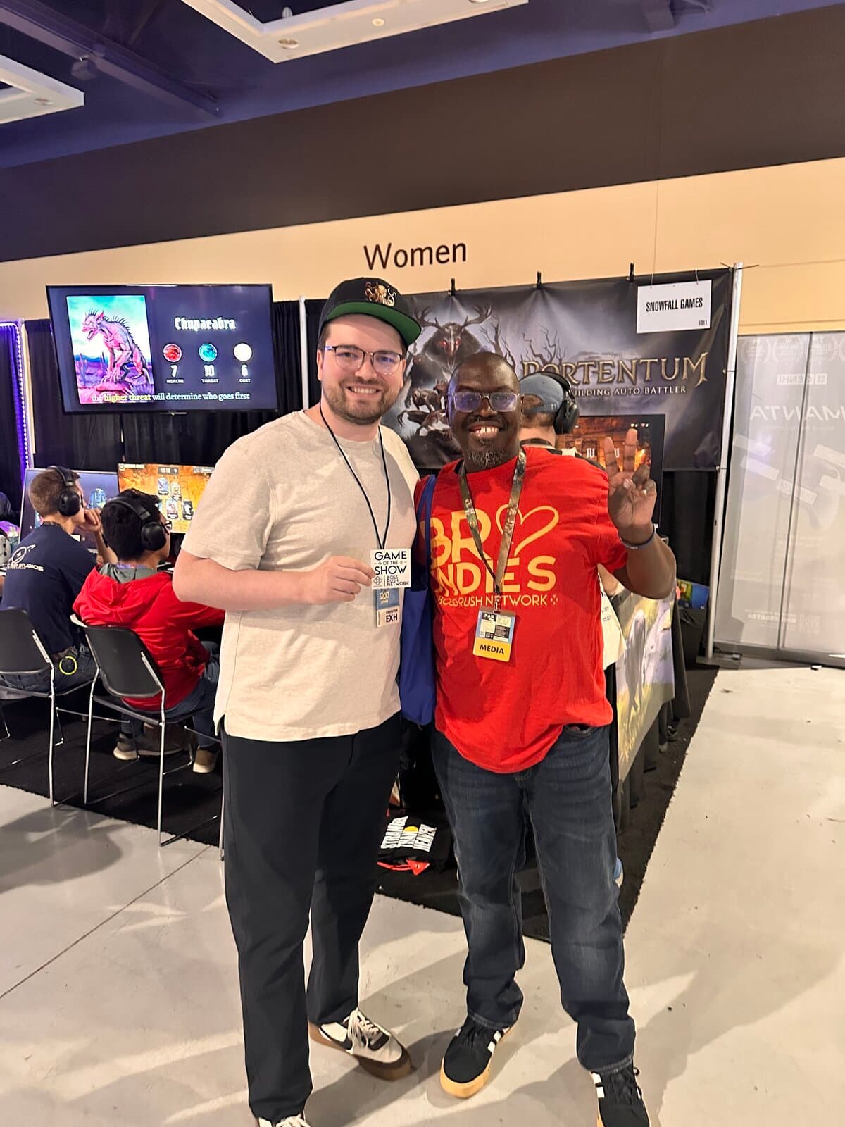 Jaden at the Portentum booth holding the Boss Rush Network Game of the Show card, standing with a writer from Boss Rush Network